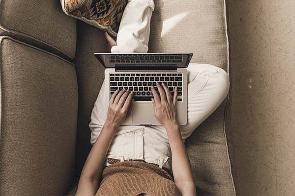 A woman on her laptop setting on her coach