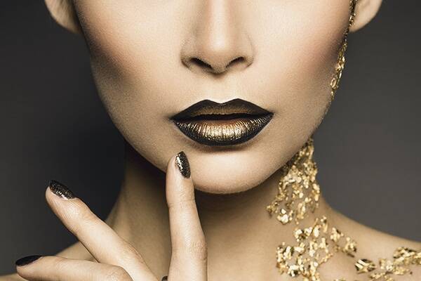 A woman's black and gold lips. with gold running down her neck